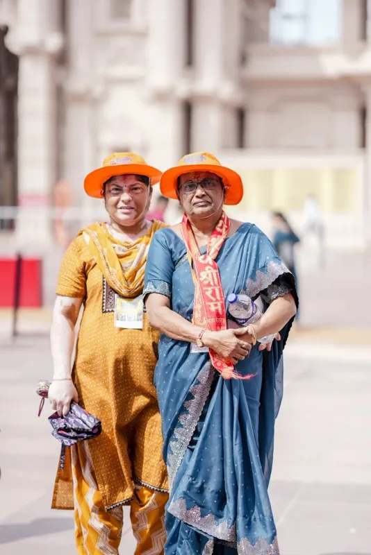 Two women pilgrims in orange hats standing together in Ayodhya