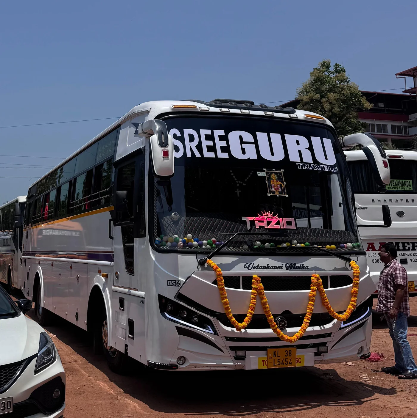 Sree Guru Travels coach decorated with marigold garlands, ready for a journey from Kannur