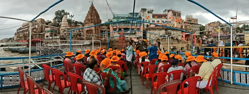 Wide view from a boat of travellers and the temples lining the Varanasi ghats