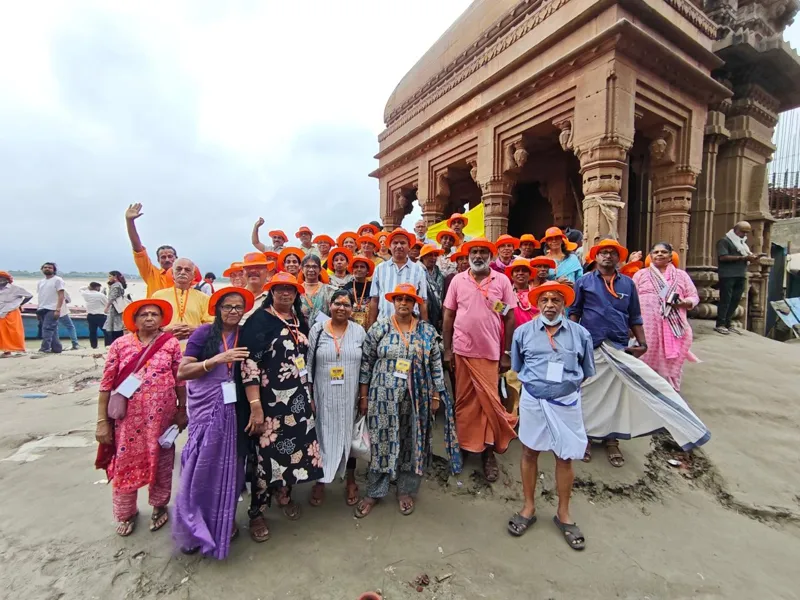Group photo of pilgrims beside an old sandstone temple on the Ganga ghats
